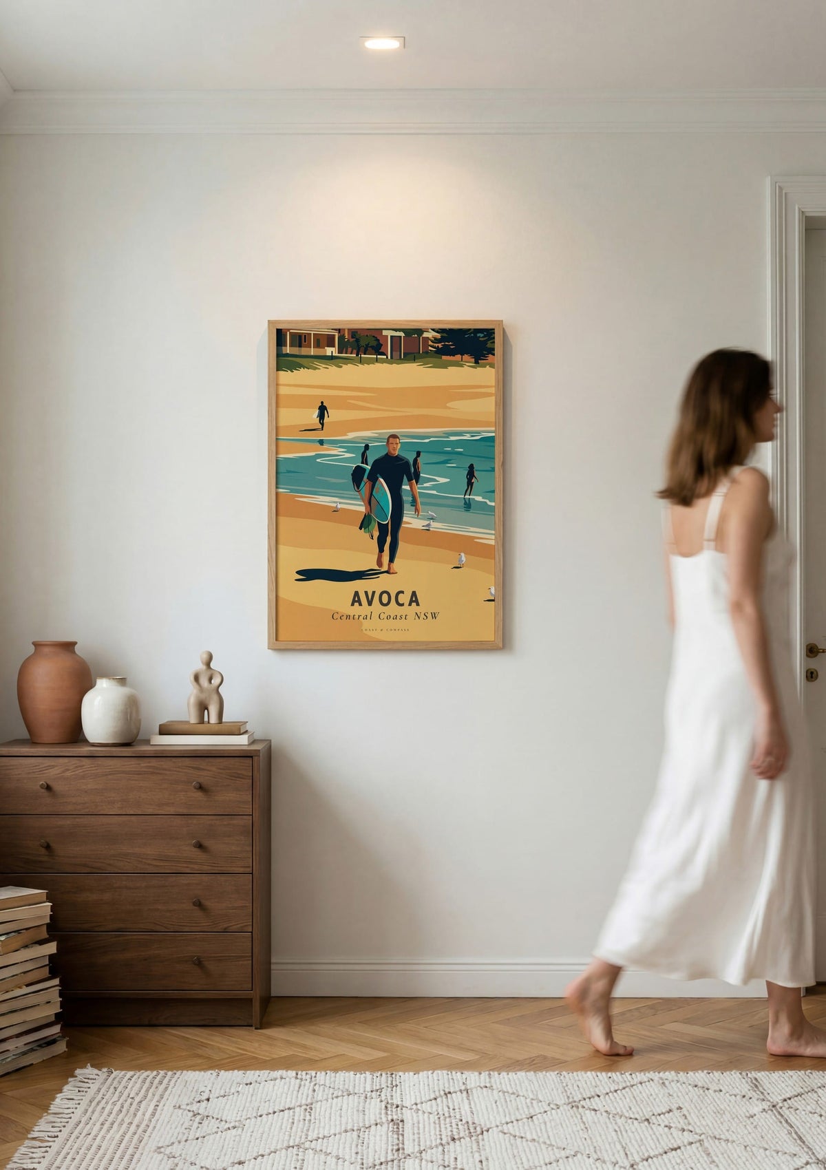 Avoca Beach Surfer travel poster shown on a wall as a woman walks past