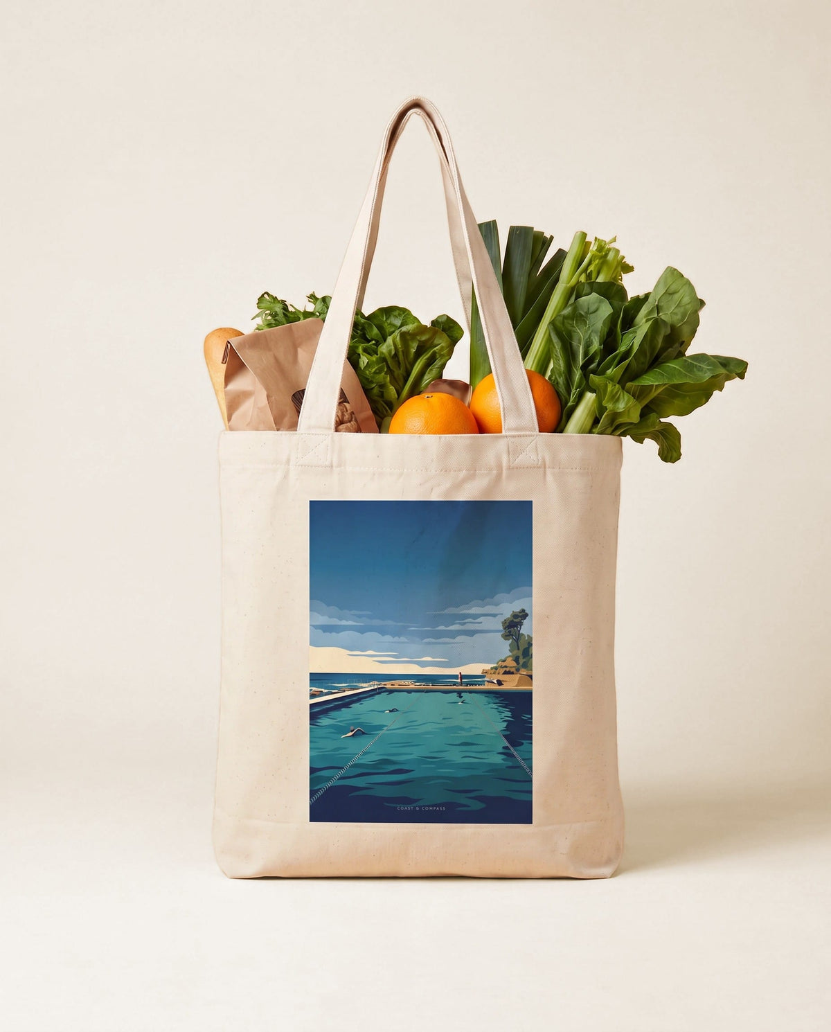Coast & Compass Lap Lines tote bag packed with fresh groceries against a teal studio backdrop, cream cotton canvas printed with the Lap Lines artwork
