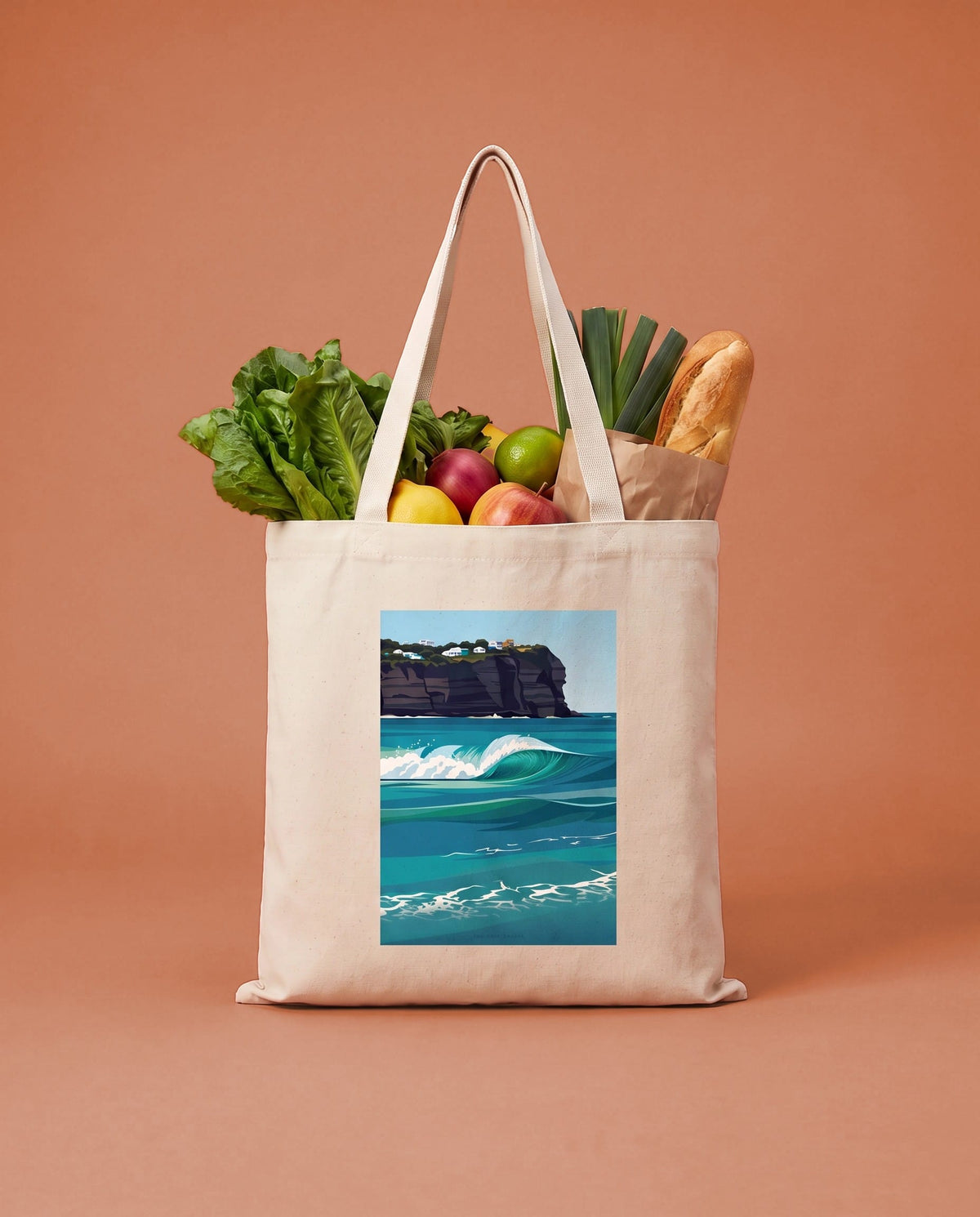 Coast & Compass Turquoise Break tote bag packed with fresh groceries against a teal studio backdrop, cream cotton canvas printed with the Turquoise Break artwork