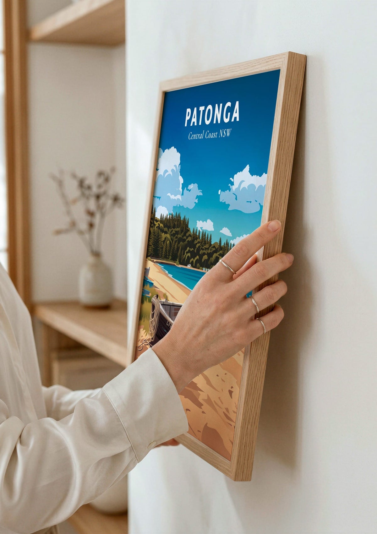 Patonga travel poster shown being hung on a wall
