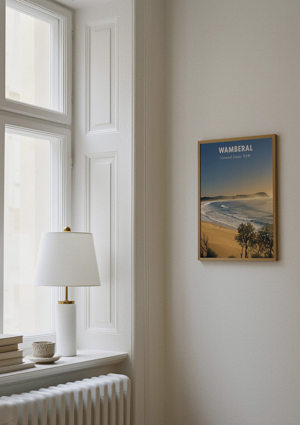 Wamberal Mist travel poster shown on a wall beside a window