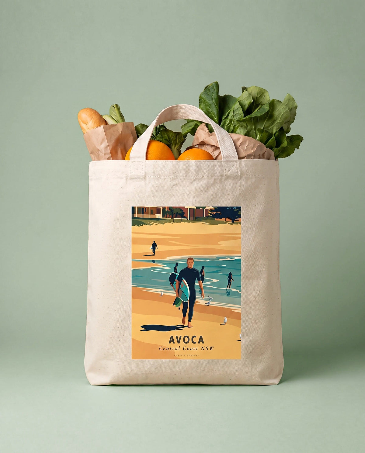 Coast & Compass Avoca Beach tote bag packed with fresh groceries against an olive studio backdrop, cream cotton canvas printed with the Avoca Beach Central Coast NSW poster design