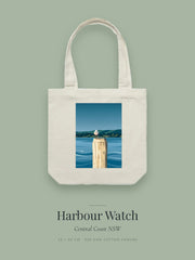Harbour Watch artwork printed on a cream cotton canvas tote bag — a seagull perched on a timber pylon above still water