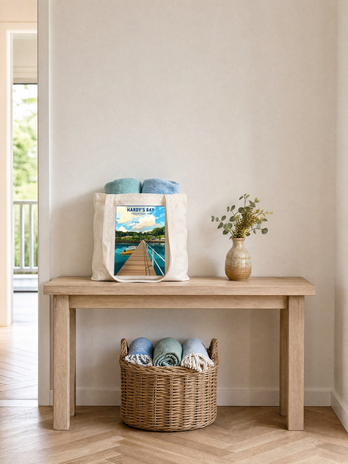 Coast & Compass Hardy's Bay tote bag on a timber hall console with rolled beach towels, printed cotton canvas