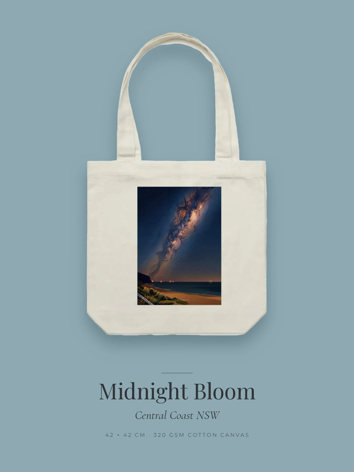 Midnight Bloom artwork printed on a cream cotton canvas tote bag — the Milky Way arcing over a dark coastline