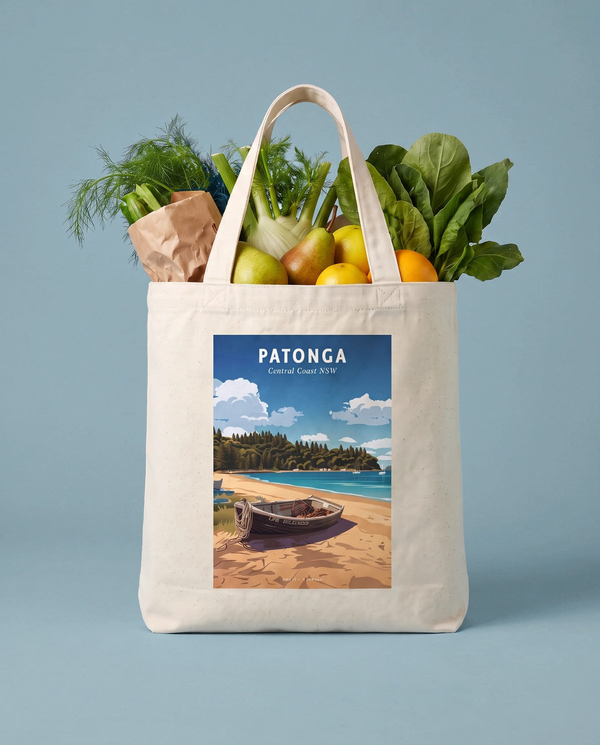 Coast & Compass Patonga tote bag packed with fresh groceries against a powder blue studio backdrop, cream cotton canvas printed with the Patonga Central Coast NSW poster design